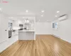 Kitchen with a wall mounted air conditioner, appliances with stainless steel finishes, light wood-type flooring, baseboard heating, and white cabinetry