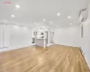 Unfurnished living room featuring sink, a baseboard radiator, an inviting chandelier, a wall mounted AC, and light hardwood / wood-style floors