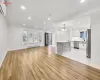 Unfurnished living room with sink, a baseboard radiator, an inviting chandelier, light hardwood / wood-style flooring, and a wall unit AC