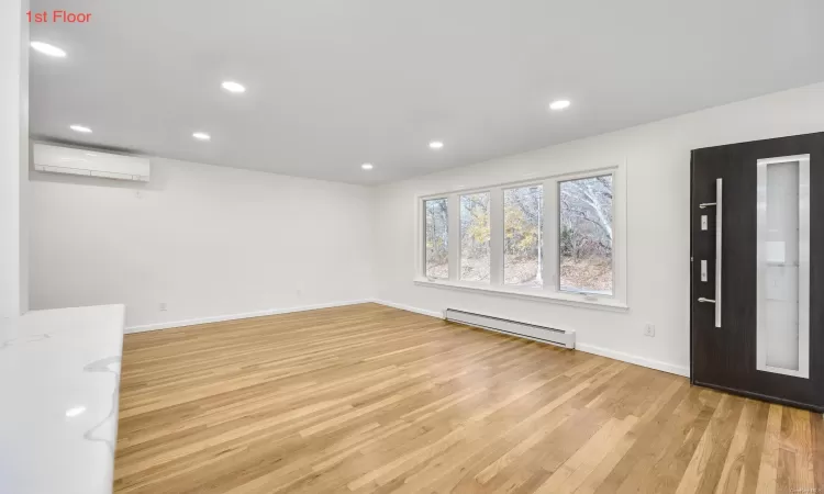 Foyer with light hardwood / wood-style floors, baseboard heating, and a wall mounted AC