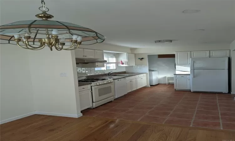 Kitchen featuring white cabinets, washer / dryer, white appliances, and dark wood-type flooring