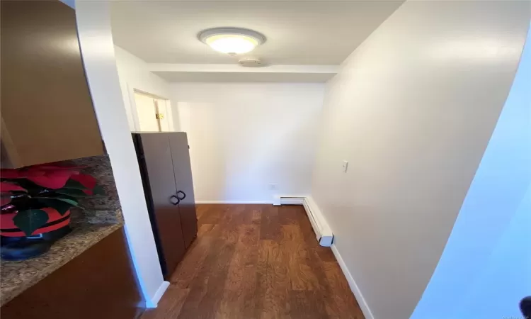 Hallway with dark hardwood / wood-style flooring and a baseboard radiator