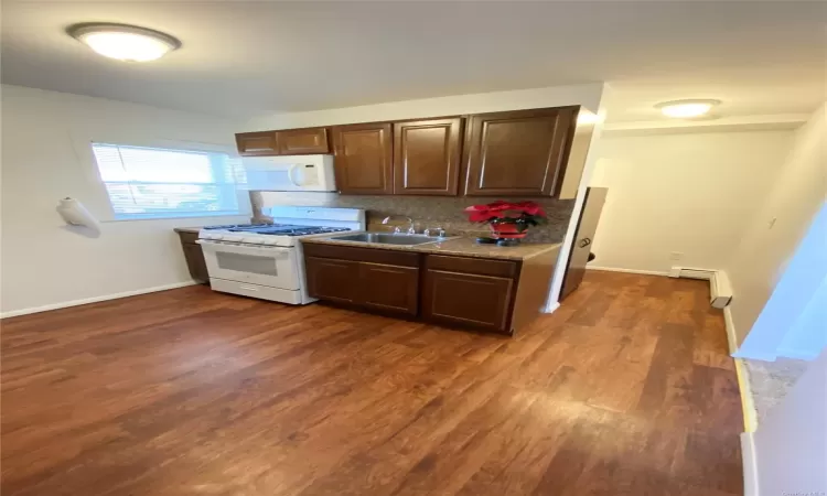 Kitchen featuring backsplash, sink, dark hardwood / wood-style floors, and white appliances