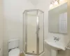 Bathroom featuring toilet, a shower with shower door, and sink