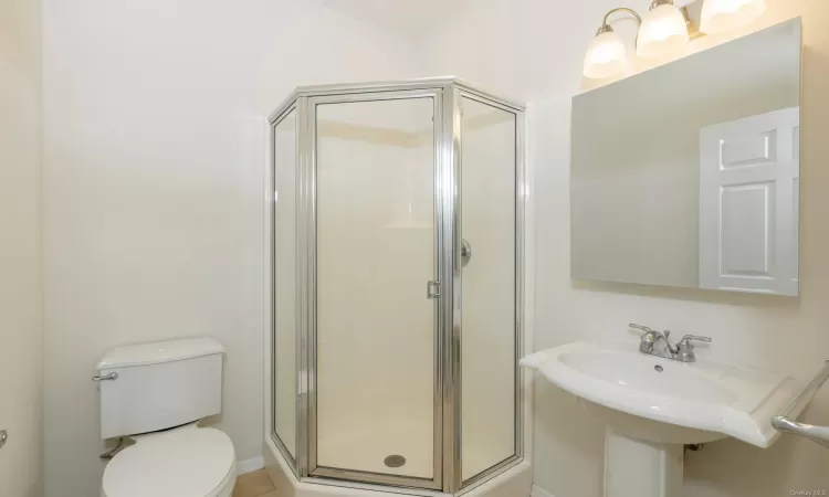 Bathroom featuring toilet, a shower with shower door, and sink