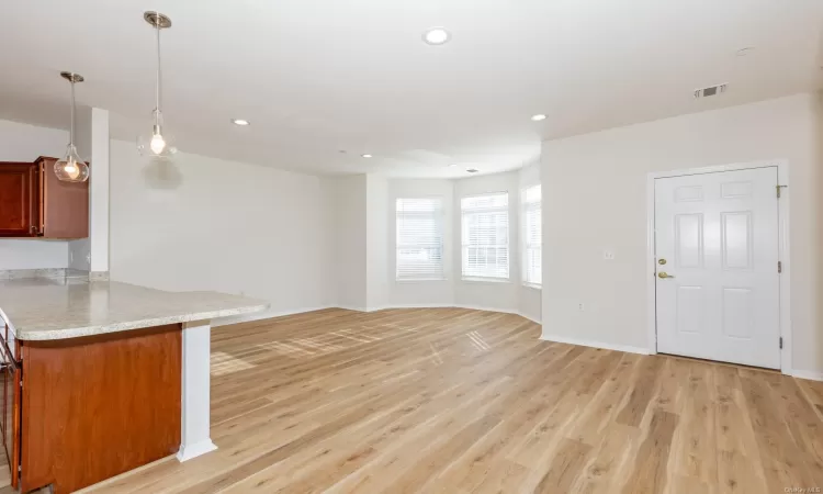 Kitchen with kitchen peninsula, hanging light fixtures, and light wood-type flooring