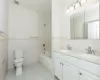 Full bathroom featuring toilet, vanity, tile patterned floors, and tile walls