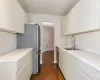 Kitchen with sink, appliances with stainless steel finishes, white cabinets, light stone counters, and dark wood-type flooring