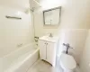 Full bathroom with tile walls, vanity, tiled shower / bath combo, and toilet