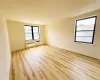 Empty room featuring a wall unit AC, radiator heating unit, and light wood-type flooring