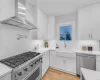 Kitchen featuring white cabinets, stainless steel appliances, and wall chimney range hood