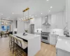 Kitchen featuring high end appliances, white cabinets, hanging light fixtures, wall chimney exhaust hood, and a kitchen island