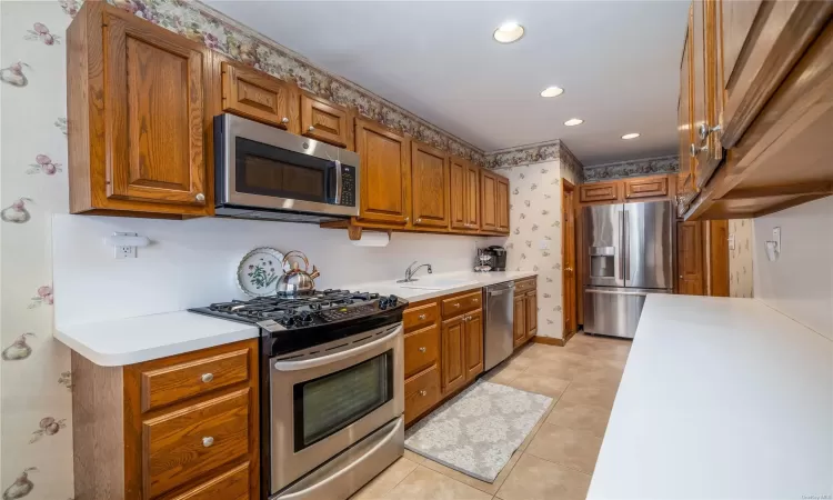 Kitchen featuring sink, light tile patterned floors, and stainless steel appliances