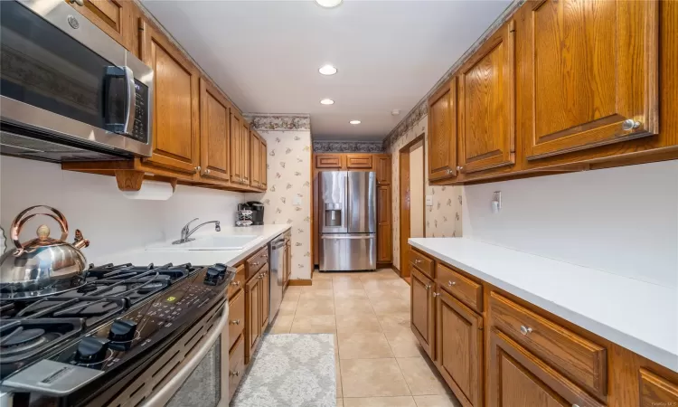 Kitchen with sink, light tile patterned floors, and appliances with stainless steel finishes