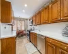 Kitchen featuring sink, a baseboard radiator, decorative light fixtures, light tile patterned floors, and appliances with stainless steel finishes