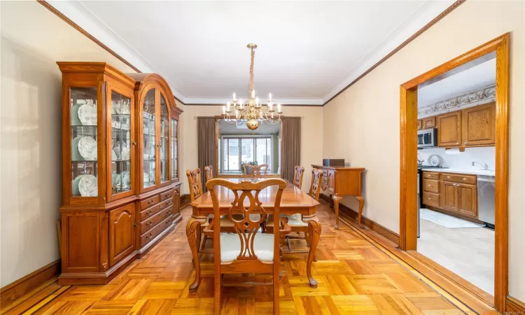 Dining area featuring light parquet flooring, crown molding, and an inviting chandelier