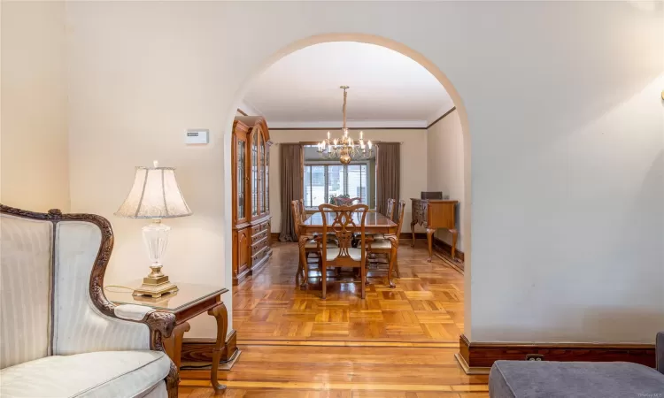 Dining area featuring light parquet floors, ornamental molding, and an inviting chandelier