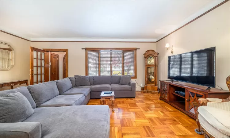 Living room featuring light parquet flooring and crown molding