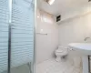 Bathroom with toilet, walk in shower, and tile walls