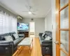 Living room with ceiling fan, a healthy amount of sunlight, an AC wall unit, crown molding, and hardwood / wood-style floors