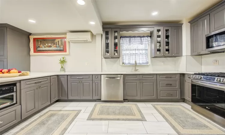 Kitchen with sink, stainless steel appliances, a wall mounted air conditioner, gray cabinets, and light tile patterned floors