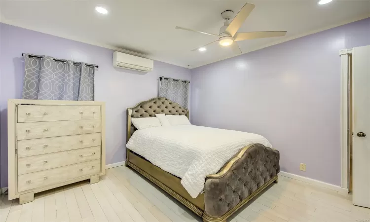 Bedroom featuring ceiling fan, a wall mounted air conditioner, and hardwood / wood-style flooring