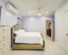 Bedroom with ceiling fan, light wood-type flooring, and a wall mounted AC