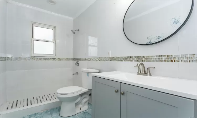 Bathroom with walk in shower, toilet, vanity, tile walls, and ornamental molding