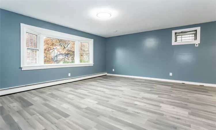 Unfurnished room featuring light hardwood / wood-style floors and a baseboard heating unit