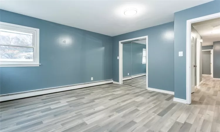 Unfurnished room featuring light hardwood / wood-style floors and a baseboard radiator