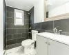 Bathroom featuring a tile shower, tile walls, and toilet