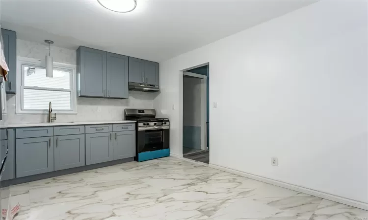 Kitchen with gray cabinets, sink, decorative light fixtures, and stainless steel range with gas stovetop