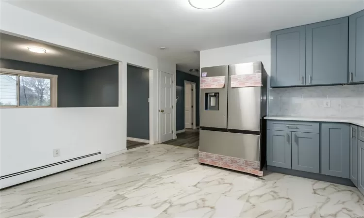 Kitchen featuring stainless steel fridge with ice dispenser, backsplash, and a baseboard heating unit