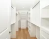 Walk in closet with light hardwood / wood-style floors