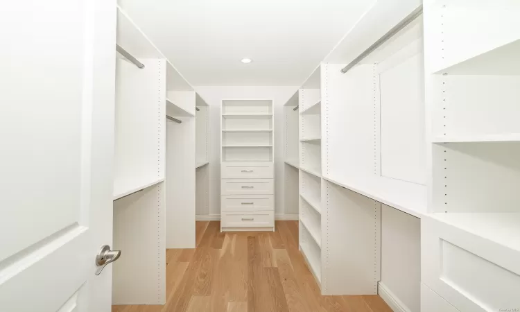 Walk in closet with light hardwood / wood-style floors