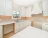 Kitchen featuring white cabinets, custom range hood, and sink