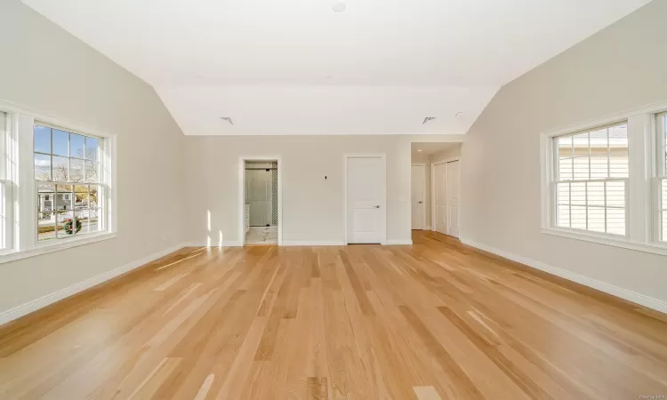 Empty room with light hardwood / wood-style flooring and lofted ceiling