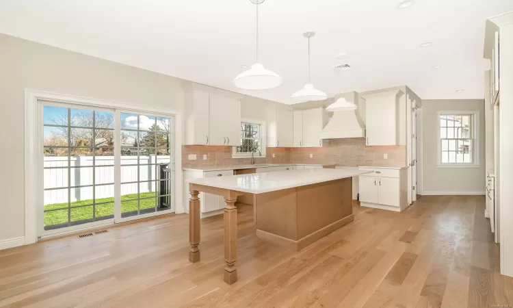 Kitchen with a center island, white cabinetry, a healthy amount of sunlight, and light hardwood / wood-style flooring