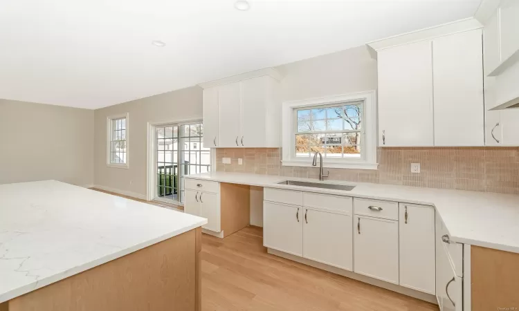 Kitchen featuring white cabinets, decorative backsplash, sink, and light hardwood / wood-style flooring