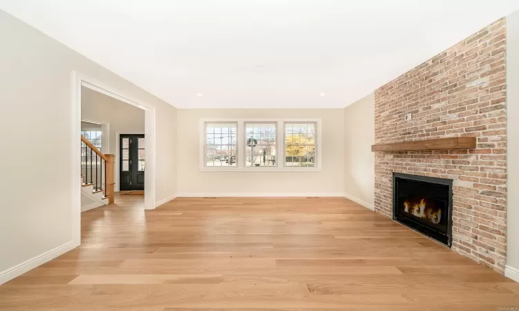 Unfurnished living room featuring a brick fireplace and light hardwood / wood-style flooring