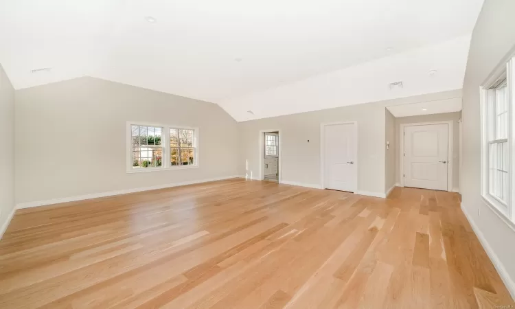 Unfurnished living room featuring light hardwood / wood-style floors and vaulted ceiling