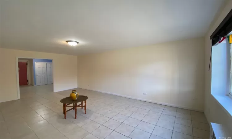 Tiled empty room featuring vaulted ceiling and radiator heating unit