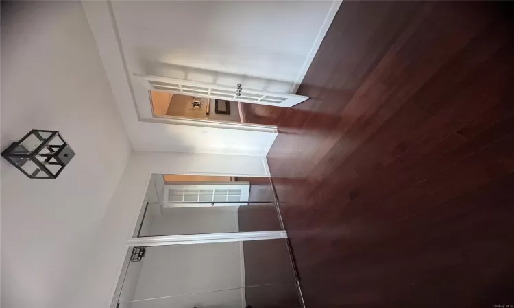 Unfurnished bedroom featuring dark hardwood / wood-style flooring, multiple closets, and french doors