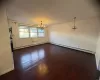 Empty room featuring dark hardwood / wood-style floors, an inviting chandelier, and baseboard heating