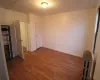 Unfurnished bedroom with dark hardwood / wood-style flooring, radiator heating unit, and connected bathroom