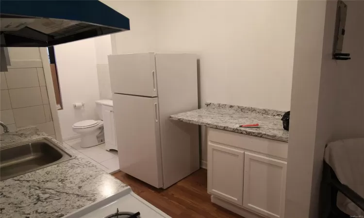 Kitchen with sink, white range with gas stovetop, range hood, decorative backsplash, and light wood-type flooring