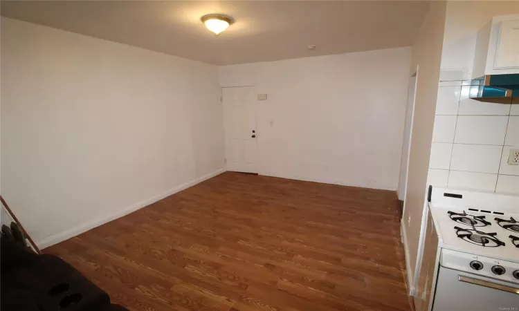 Unfurnished bedroom with radiator heating unit and hardwood / wood-style floors