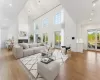 Living room with a high ceiling, an inviting chandelier, light hardwood / wood-style flooring, and sink