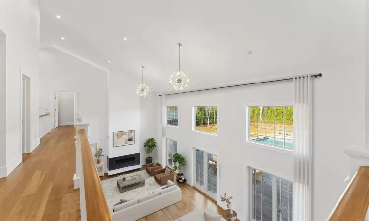 Living room featuring light wood-type flooring, high vaulted ceiling, and a notable chandelier