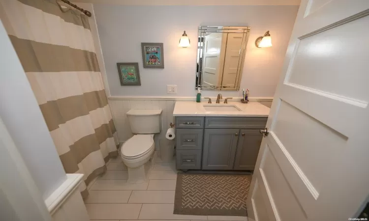 Kitchen featuring stainless steel appliances, dark wood-type flooring, white cabinets, a sink, and light stone countertops